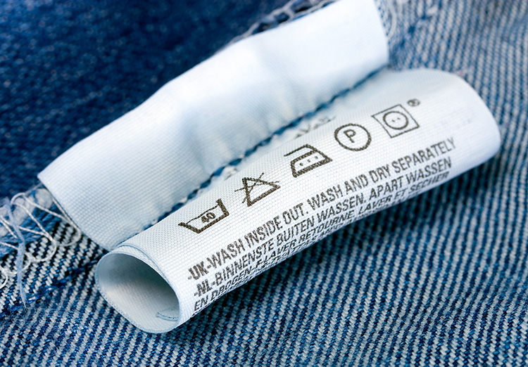 Wassymbolen kleding betekenis wit label in spijkerbroek met symbolen