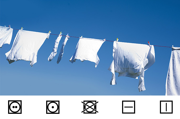 Wassymbolen drogen witte kleren hangen aan een waslijn tegen blauwe lucht